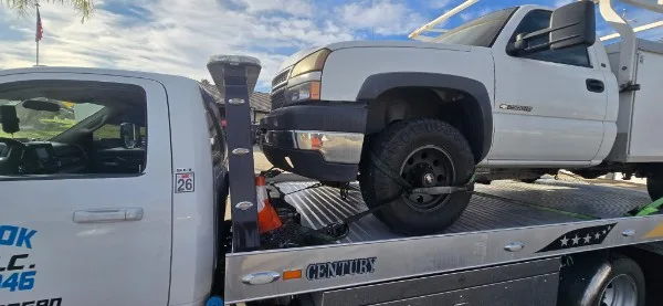 Fast Hook Towing flatbed towing a lifted Chevy Silverado work truck