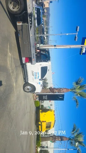 Fast Hook Towing flatbed transporting a sedan on a commercial street