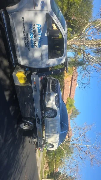 Fast Hook Towing flatbed towing a sedan on a residential street