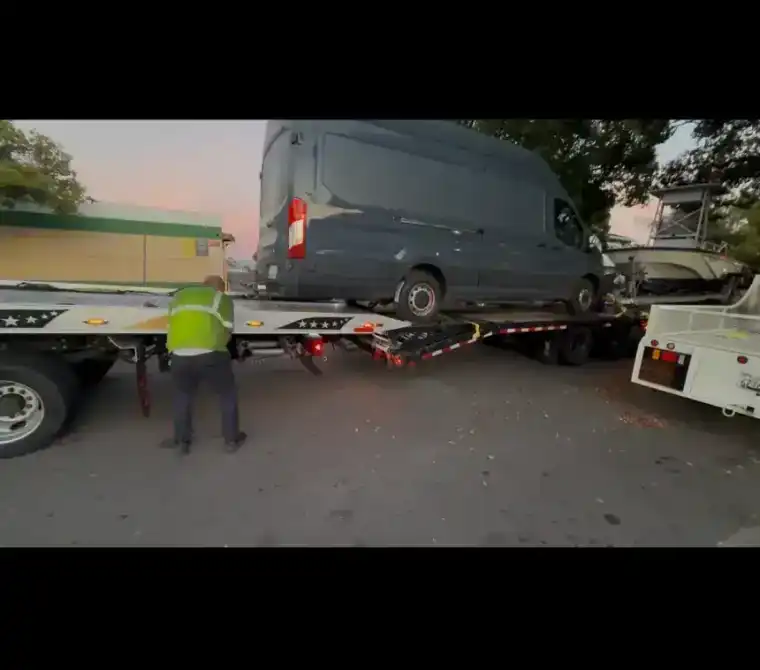 Fast Hook Towing worker loading Ford Transit onto flatbed truck